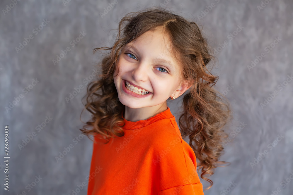portrait of a happy girl with big blue eyes in a yellow top with ponytails on a gray background portrait of a happy girl with big blue eyes in a yellow top with ponytails on a gray background