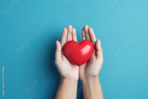 A person holds a red heart in their hands. This image can be used to convey love  care  and affection