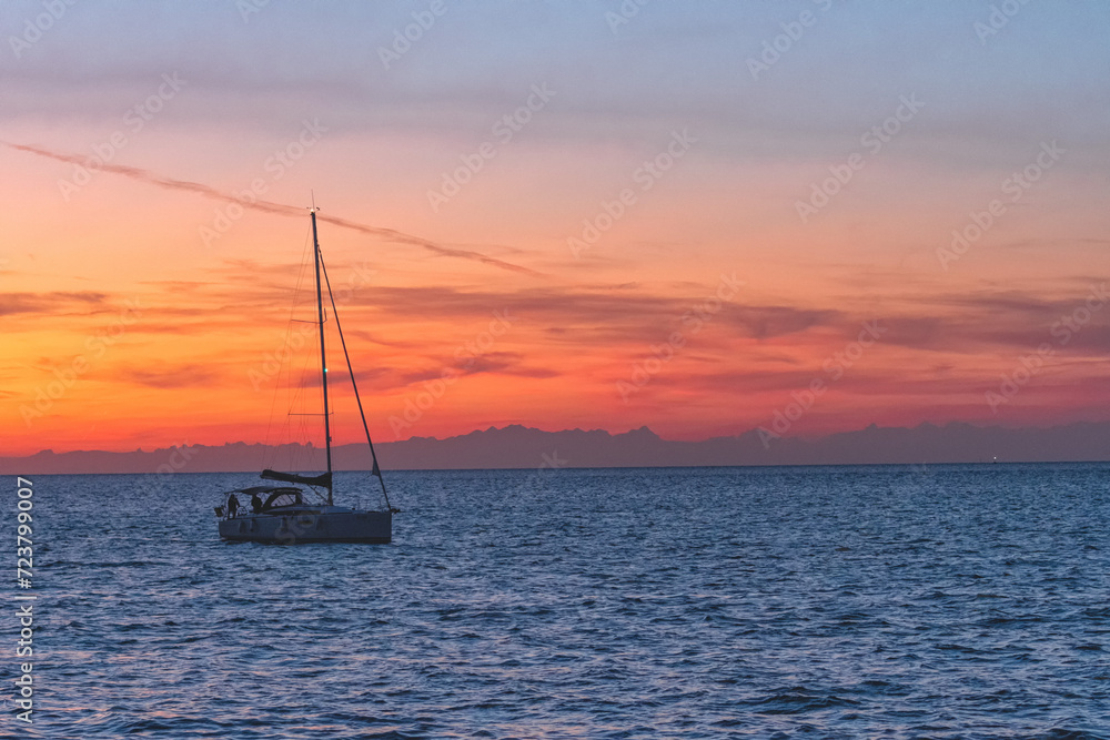 Sailing boat on the sea in summer with sunset sky