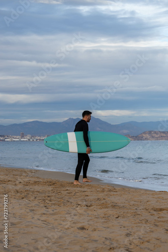 surfer wearing neoprene and surfboard on the beach