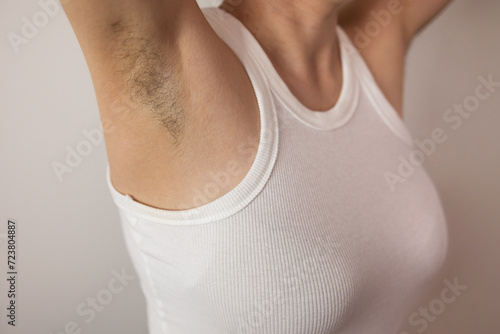 Raised hand with hair under the armpits. Feminism, Freedom, Skin Care, Feminism, Body Positivity, Naturalness, Hygiene. Depilation, shaving hair with a razor. Hairy underarms