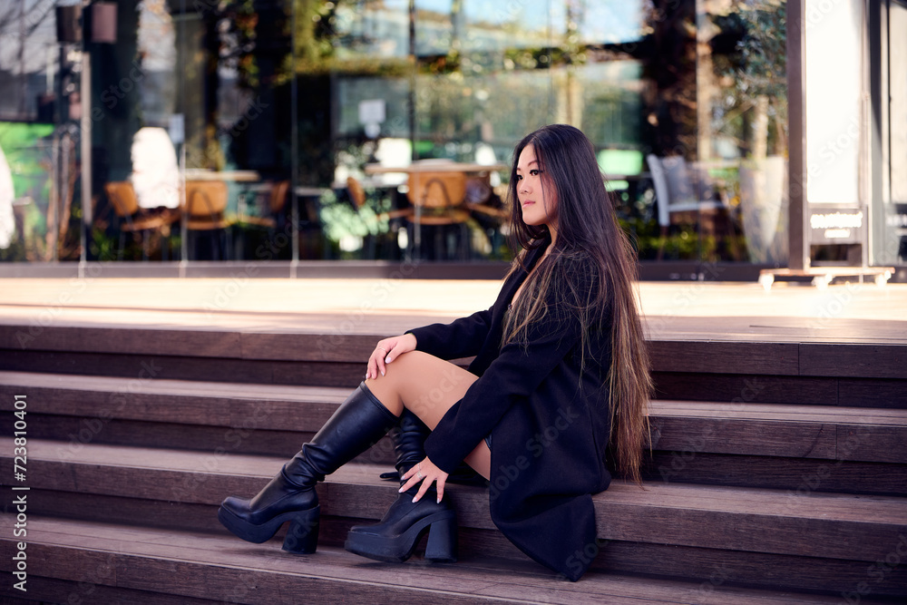 Portrait of a beautiful young Asian woman in a black coat and boots
