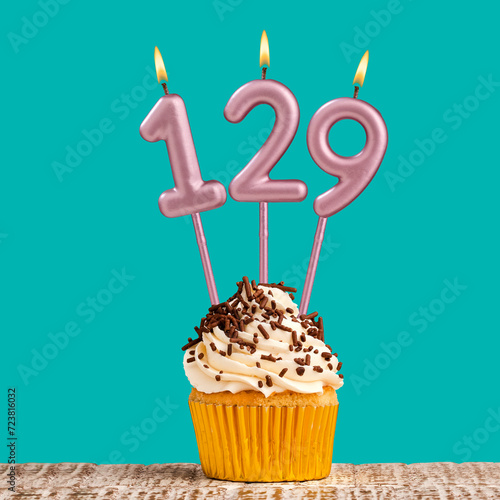 Birthday card with number 129 candle on aquamarine background