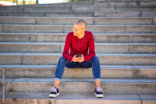 woman sitting on steps using phone © mimagephotos