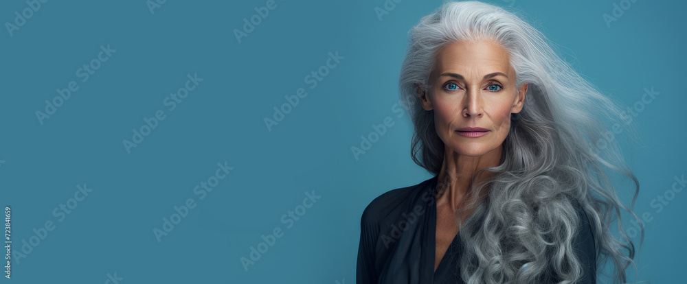 Elegant, smiling, elderly, chic, woman with gray long hair and perfect skin, on a blue background, banner. Advertising of cosmetic products, spa treatments, shampoos and hair care products, dentistry
