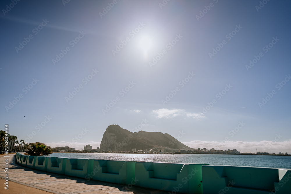 Santa Margarita, Spain - January 24, 2024 -  iconic Rock of Gibraltar, with a seaside promenade in the foreground under a clear and sunny sky.
