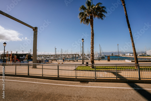 Santa Margarita, Spain - January 24, 2024 - road leading towards "La Linea" and "Gibraltar" with palm trees, traffic signs, cars, a marina, and a mountain in the background.