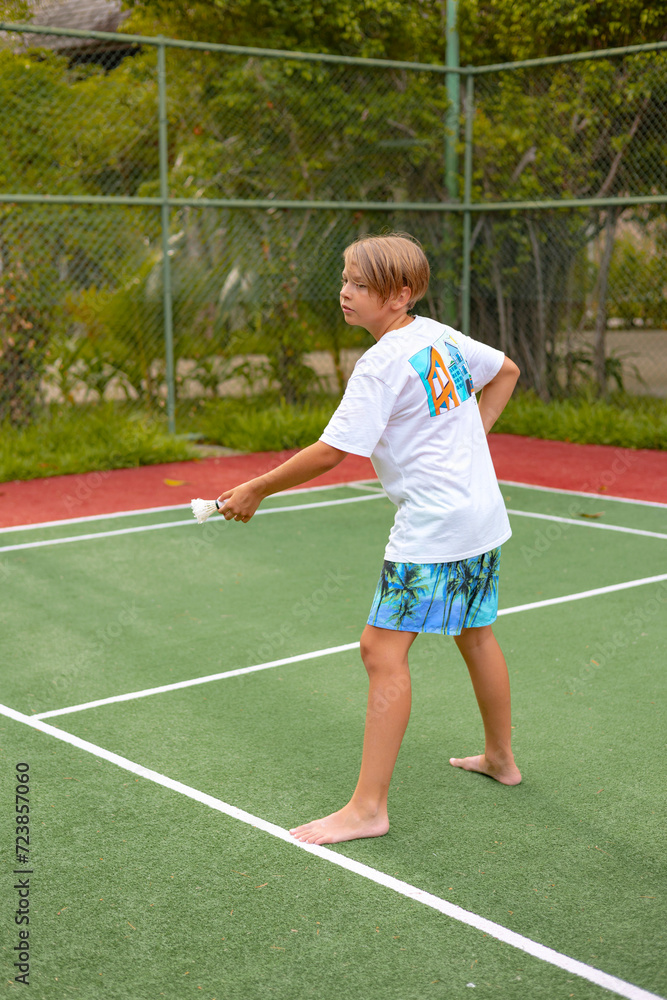 boy plays badminton outdoors in the fresh air, throws a shuttlecock and holds a racket, an island in the Maldives, active recreation and sports.