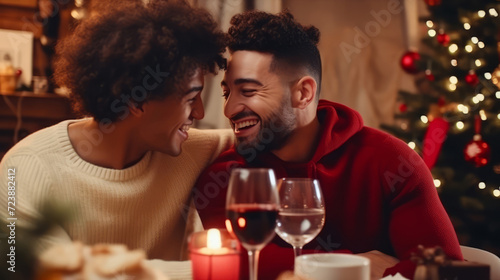 Young cheerful multiethnic gay couple sitting at Christmas table