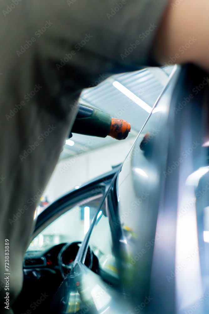close-up, the master applies a protective film for tinting to the glass dries it car detailing - obrazy, fototapety, plakaty 