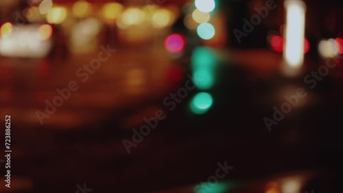 Wet city street with traffic lights refections at night in Paris