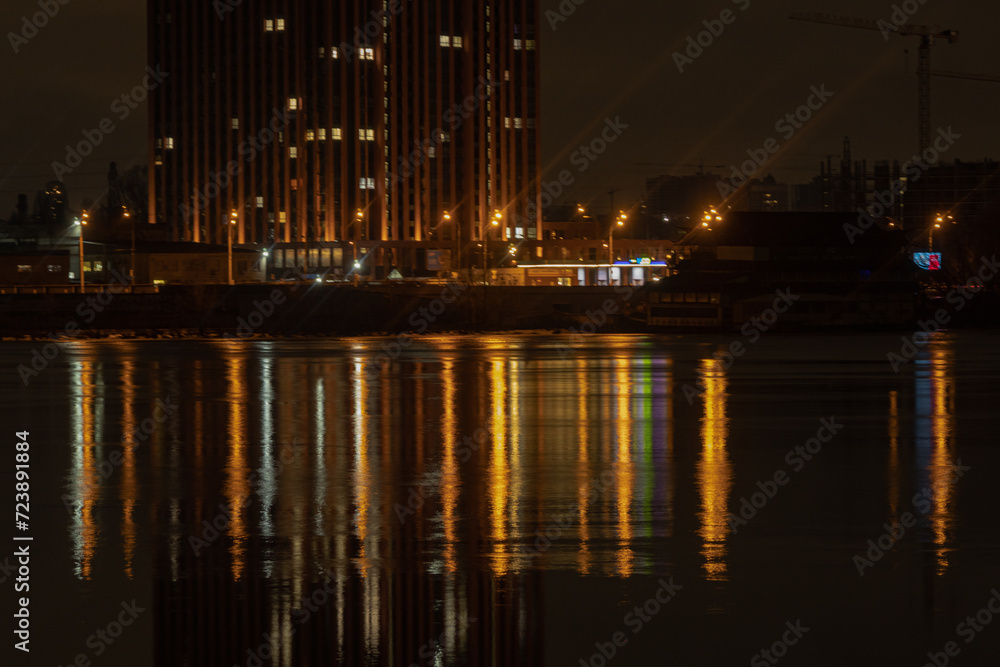 KYIV, UKRAINE - JANUARY 28, 2024: Kyiv in the evening and Dnipro river. the light from the windows reflects well on the water. walk from the embankment to the right bank of Kyiv and the bridge.