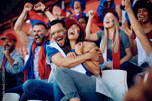 Fototapeta Naklejka Na Ścianę i Meble -  Group of cheerful sports fans celebrating victory of their favorite team while spectating game from stadium stands.
