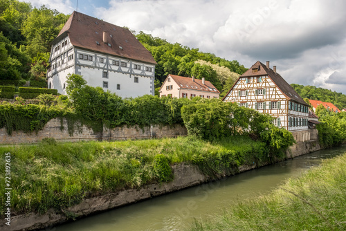 Historische Gebäude mit Fachwerk Neckarburg und Neckarmühle an Neckarkanal vor Wolkenhimmel in Neckartenzlingen.