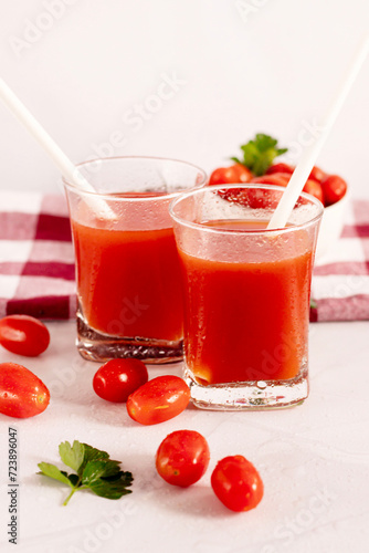 Tomato juice in a glass and fresh tomatoes. on a white background. food