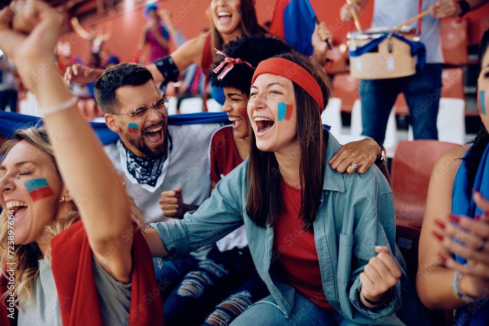 Cheerful sports fan and her friends celebrating during match at stadium. Cheerful sports fan and her friends celebrating during match at stadium.