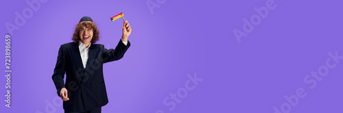 Jewish man with grogger posing against purple against purple studio background with negative space to insert text. Purim, business, festival, holiday, celebration Pesach or Passover, Judaism concept. photo