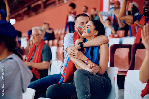 Young couple in love watching sports game at stadium.