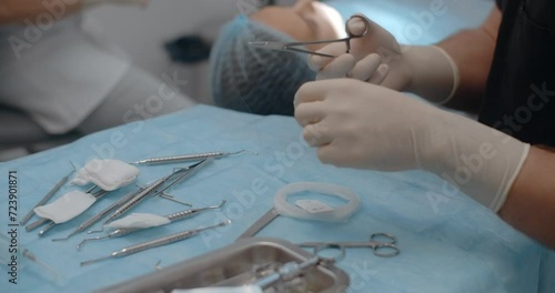 Oral surgeon prepares the instrument and surgical thread for surgery