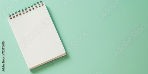 Background with copy space and a single recycled paper notepad on the left against an aqua background, embodying sustainability and eco-friendly stationery.