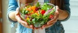 A fresh, colorful salad held in a person's hands, denoting healthy eating
