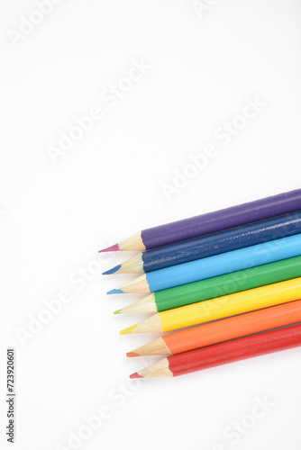 A set of wooden pencils in colours of the rainbow.  Red, orange, yellow, green, blue, indigo, and violet. Arranged in a line on white background. Close Up.