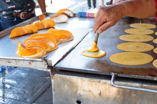 A vendor is applying flour to an iron pan to make “Thai Crispy Pancake or Kanom Buang. A traditional Thai dessert menu with crispy flour and foi thong filling. It is popular form of Thai street food
 photo