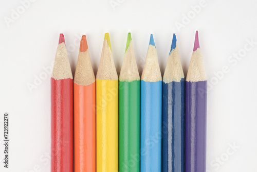 A set of wooden pencils in colours of the rainbow.  Red, orange, yellow, green, blue, indigo, and violet. Arranged in a line on white background. Close Up.