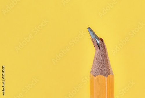 Broken or damaged wooden pencil tip or graphite on yellow background with copy space