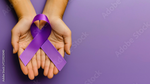 Two hands holding awareness ribbon, purple background, top view, copy space on the right photo