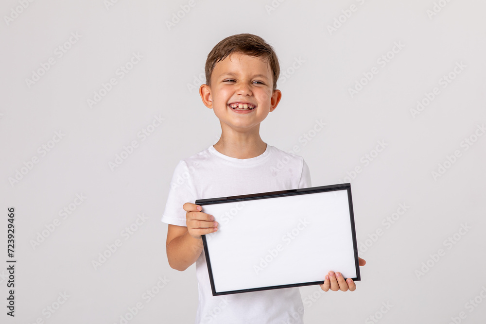 portrait of happy laughing baby boy holding white drawing Board on white background, young boy is holding a drawing board in her hands. white isolated background. Mock up. Copyspace. portrait of happy laughing baby boy holding white drawing Board on white background, young boy is holding a drawing board in her hands. white isolated background. Mock up. Copyspace.