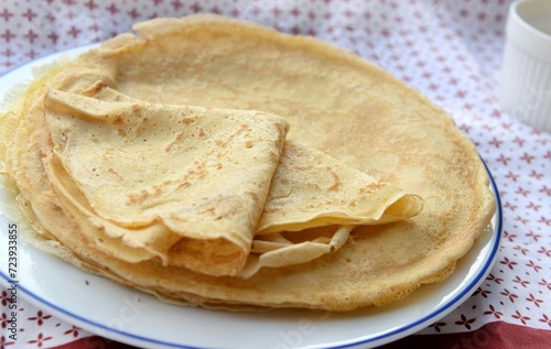 traditional french pancake homemade- folded crepe in a plate on a red and white tablecloth