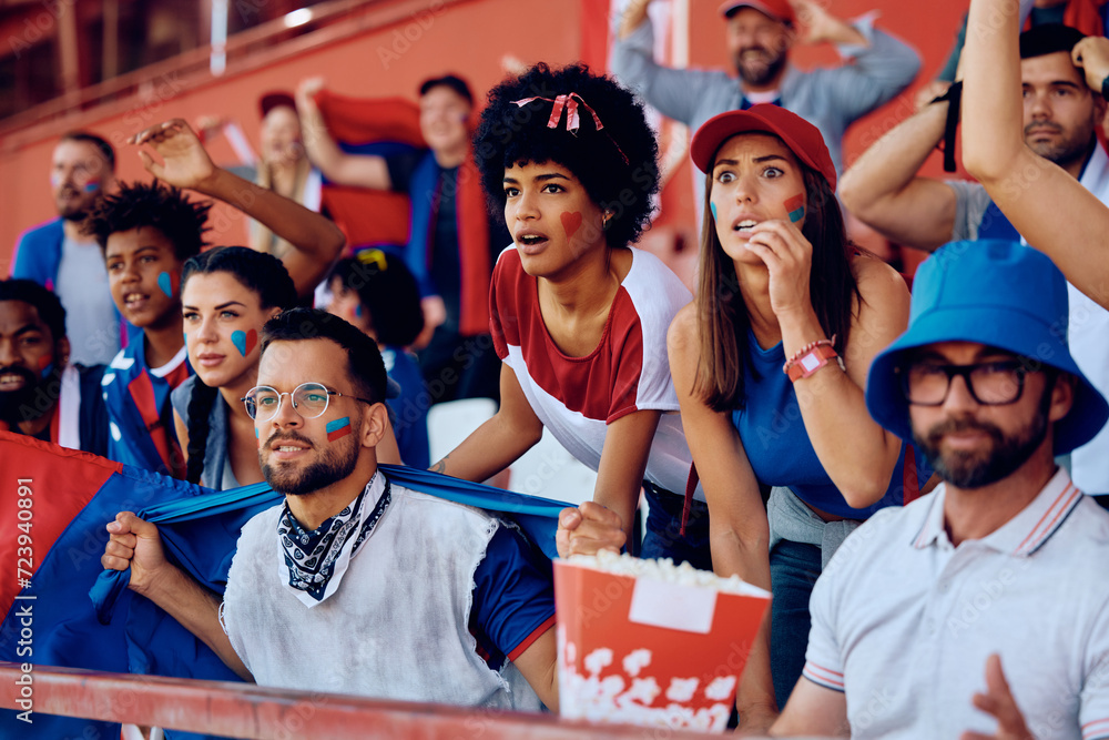 Multiracial group of spectators watching sports match on stadium. - obrazy, fototapety, plakaty 