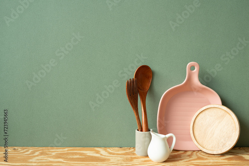 Kitchen ceramic dish plate, coaster, cutlery holder on wooden shelf. green wall background photo