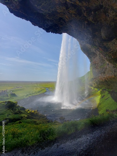 Open cave with a waterfall spraying out of the side. Iceland
