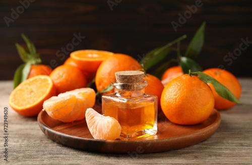 Bottle of tangerine essential oil and fresh fruits on wooden table