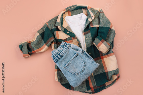 Children's checkered shirt and blue jeans on a pink background. photo