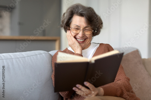 Senior woman in glasses resting on sofa and enjoy reading book, spending free time on retirement at home, free space