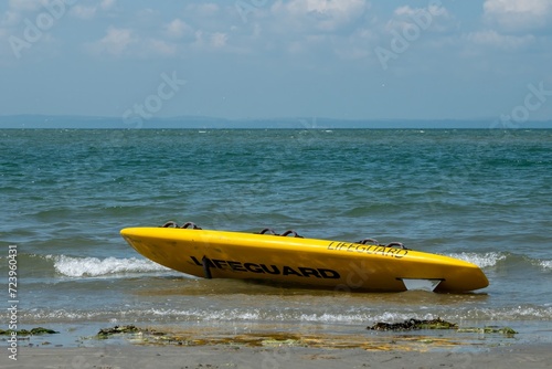yellow lifeguard surf rescue board on beautiful sandy beach with the sea in the background