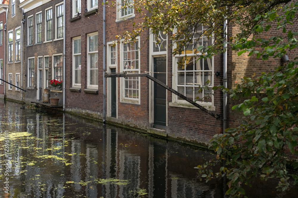 Voldersgracht canal with its typical buildings reflected on the water in the old town of the beautiful city of Delft, Netherlands, in a sunny day.