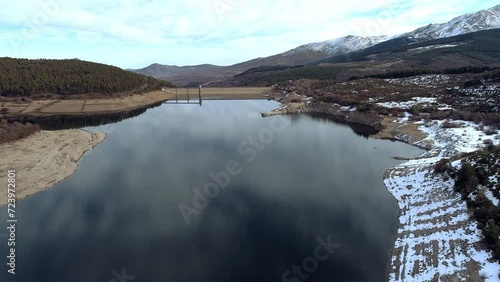 aerial view of a reservoir in autumn with snow-capped mountains
