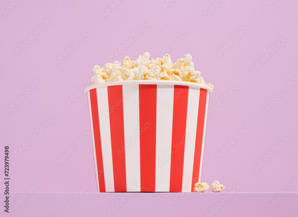 A big striped bucket of popcorn. Friendly weekend trip to the cinema.