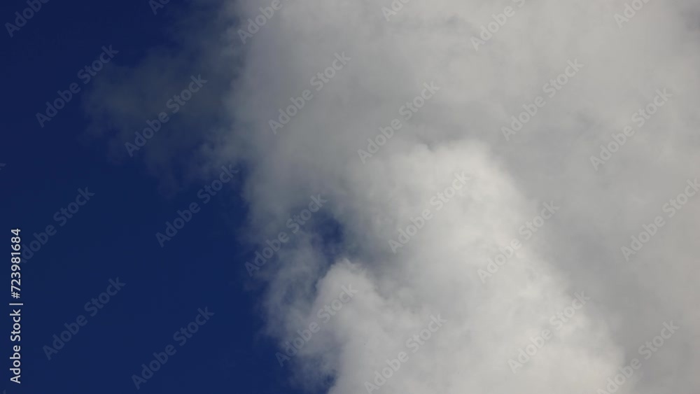 White cloud moves quickly and changes shape against the blue sky. Cloud movement in close-up, convection processes in the atmosphere. Growing and Moving White Cumulus Clouds, Air Convection