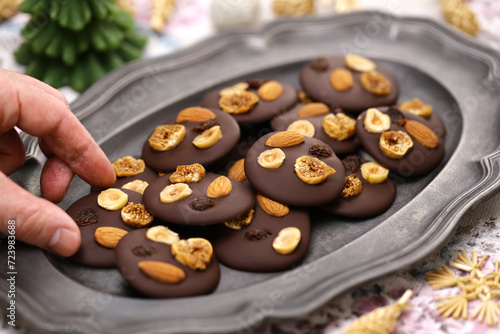 homemade chocolate mendiants with traditional toppings; almonds, raisins, hazelnuts, fig.   French Christmas sweets.