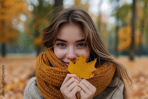 Smiling woman sitting in a park holding an autumn leaf, Belarus