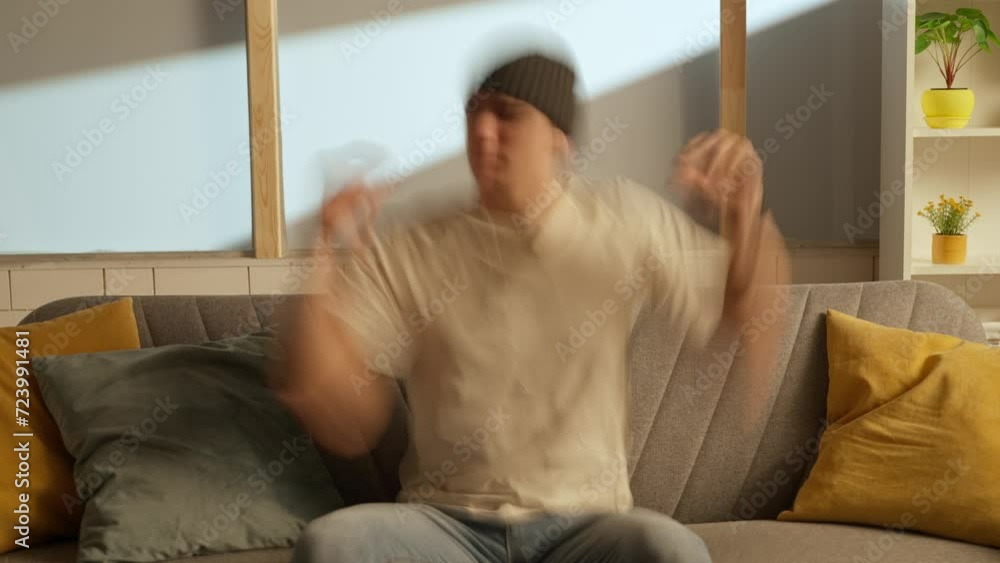 Portrait of young person in the room sitting on the couch. Man sitting on the sofa in earphones heavily jams to music dances. Double exposure. Portrait of young person in the room sitting on the couch. Man sitting on the sofa in earphones heavily jams to music dances. Double exposure.