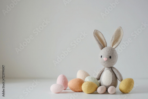 A soft, plush bunny toy displayed alongside a collection of multicolored pastel Easter eggs on a clean white background
