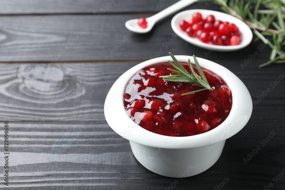 Fresh cranberry sauce in bowl and rosemary on black wooden table, closeup. Space for text Fresh cranberry sauce in bowl and rosemary on black wooden table, closeup. Space for text