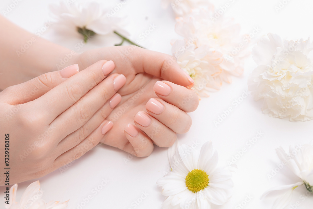 Stylish trendy nail young woman hands pink manicure on white background with flowers, banner cosmetic and beauty care