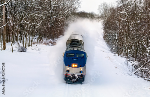 Amtrak passenger train in deep snow banking slightly through a high speed turn in Michigan photo
